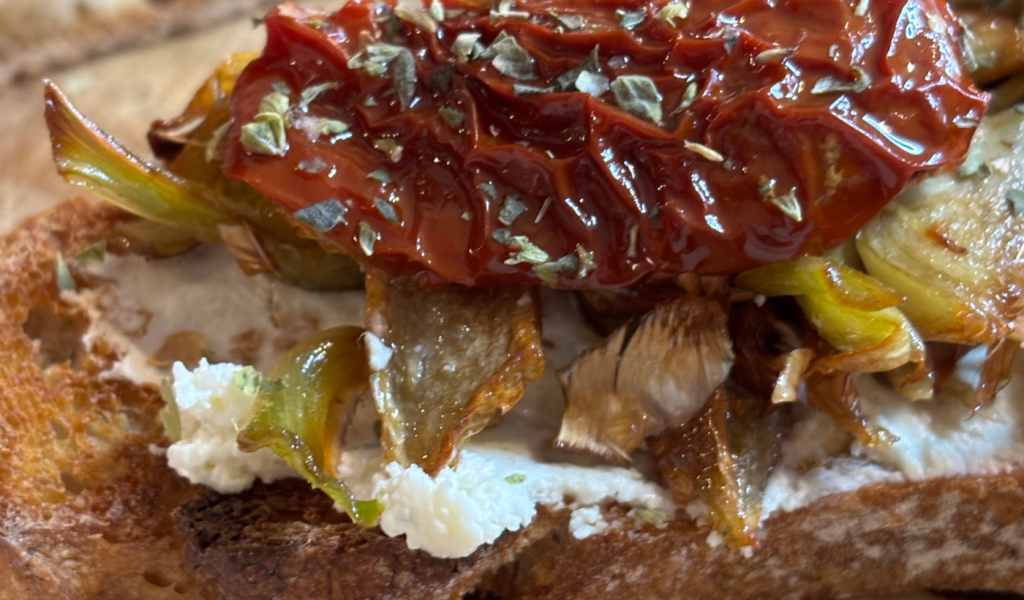 Tostada con Cremette Finas Hierbas, alcachofas y tomates secos.